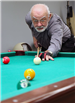 Elderly Man Prepares to Hit the Cue Ball in a Game of Pool