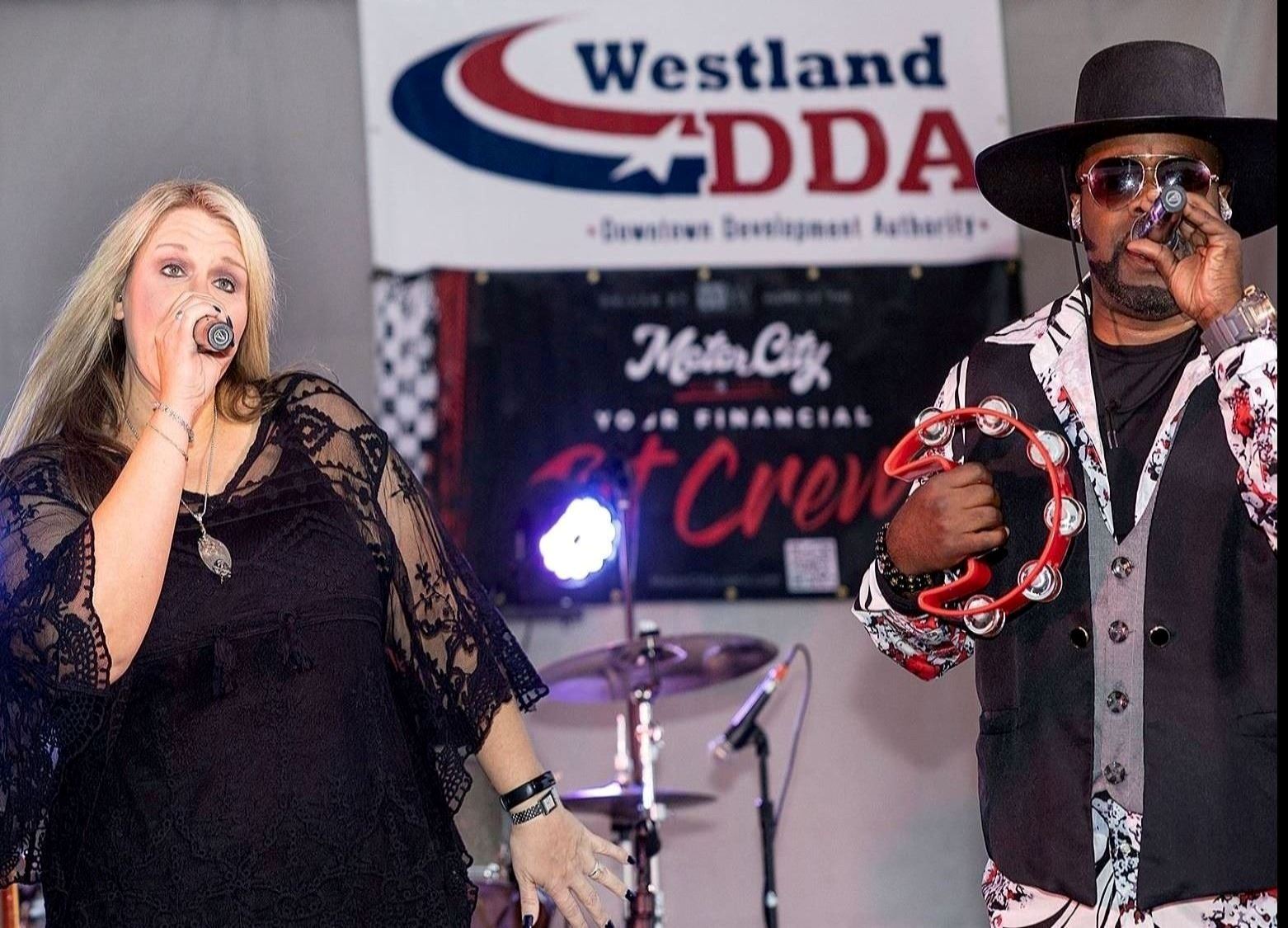 At the Craft Beer Festival, a man playing tambourine and singing and a woman singing