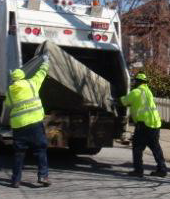Two City Workers Lifting a Couch into Their Dump Truck